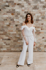 Beautiful lady in black-and-white dress posing near white brick wall. Beauty, fashion concept.