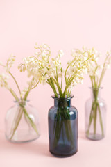 Greeting card with white lily of the valley on pink background for celebration Mothers Day, wedding, March 8. Nature concept. Home garden in vase. Summer green floral design. Selective focus.