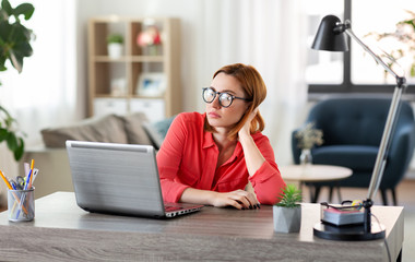 remote job, technology and people concept - bored or tired young woman in glasses with laptop computer working at home office