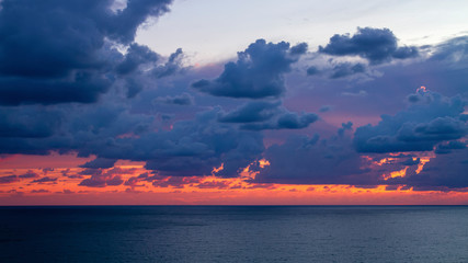 Orange and purple clouds over the blue sea at sunset