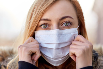 health, safety and pandemic concept - young woman wearing protective medical mask outdoors