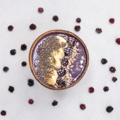 Top view of healthy breakfast blackberry smoothie with frozen banana and sunflower and chia seeds in a coconut bowl