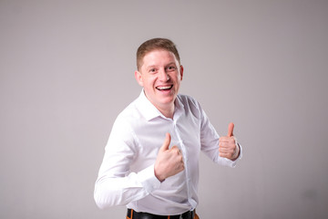 Man in a white shirt on a gray background stands and smiles posing