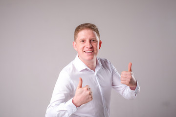 Man in a white shirt on a gray background stands and smiles posing