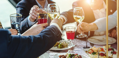 People at the table raise a toast. Close-up glasses
