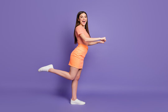 Full length profile photo of funny lady shopper leading rolling imaginary store trolley cart wear casual orange striped t-shirt jeans mini skirt isolated pastel purple color background