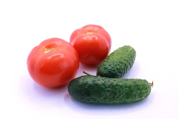 Photo of ripe tomatoes and cucumbers on a white background, close-up