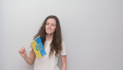 Happy girl holding Ukrainian flag on the grey background.
