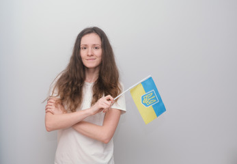 Happy girl holding Ukrainian flag on the grey background.