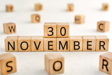 November 30 - from wooden blocks with letters, important date concept, white background random letters around