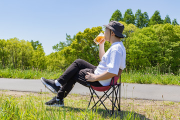 屋外でビールを飲む日本人男性。青空背景