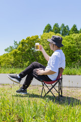 屋外でビールを飲む日本人男性。青空背景