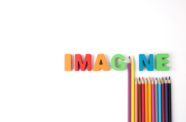  " IMAGINE " Multicolored Wooden Letters with Multicolored Pencil on White Background, Copy Space                                                              