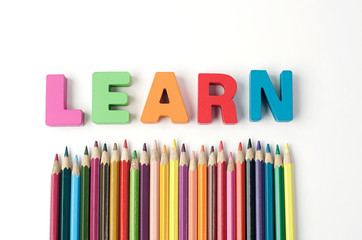  Multicolored Letter Wood ' LEARN ' with Multicolored Pencil on White Background                                                                                           