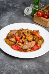 Eggplant with meat in sauce in a white plate on a gray background