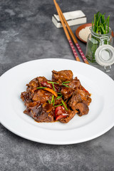 Braised lamb with vegetables in a white plate on a gray background