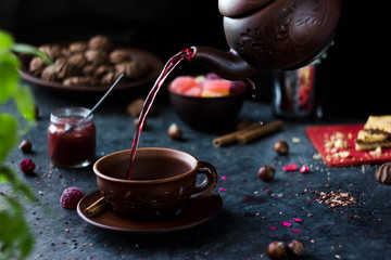 Pink tea is poured into a mug from the teapot. Red tea is poured from above. Female hand dares...