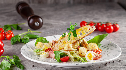 Italian Cuisine. Caesar salad with chicken, bacon, quail eggs, bread croutons, cherry tomatoes. Dish in a restaurant on a white plate. background image, copy space text