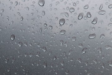 Background of raindrops on the hood of a metallic color car