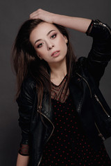 fashion model woman in a black jacket on a gray background