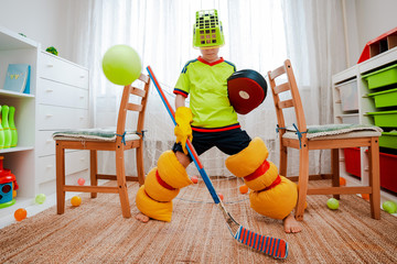 A child boy plays hockey at home having made a form with his own hands from improvised home tools...