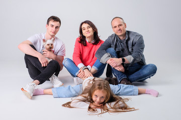 family plays with a dog on a light background on the floor
