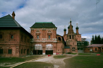 Krutitskoe Podvorye - ancient Russian monument of architecture, cloudy sky, green grass, ancient orthodox church.