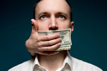 The mouth of a business man in a white shirt is covered with money