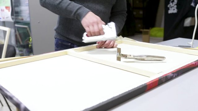 Canvas stretching. Wooden stretcher bar, staple gun, canvas pliers, male hands