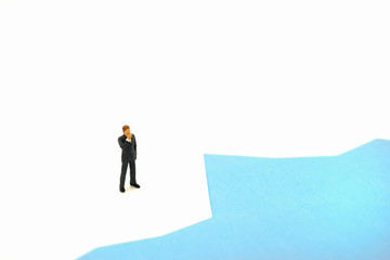 A miniature figure businessman standing and thinking on paper graph background with copy space using for business,marketing and financial concept.
