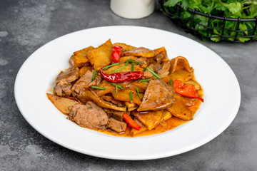 Braised beef with potatoes in a white plate on a gray background