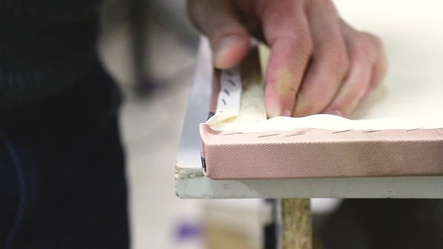 Canvas stretching. Wooden stretcher bar, staple gun, canvas pliers, male hands