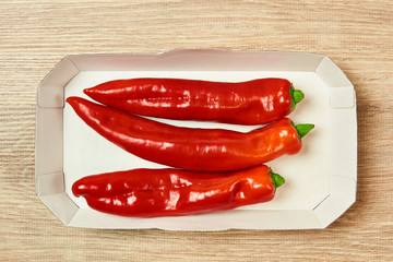 three pods of sweet pepper lie in a cardboard tray on the table