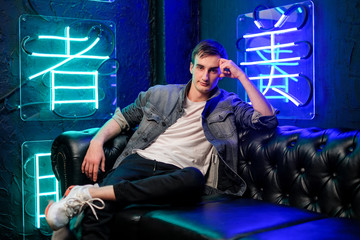 man on a leather sofa in neon light