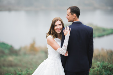 Beautiful romantic wedding couple of newlyweds hugging in park