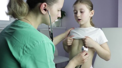 Family modern woman doctor in the office listens to the lungs of a child with a phonendoscope, a girl of Caucasian appearance of seven years. check for coronavirus, covid-19 - Powered by Adobe