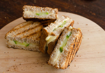 grilled sandwich with cheese and cucumber on a wooden tray