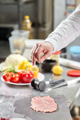 Chief chops and marinates pork. Professional chef in a kitchen of restaurant cooking.