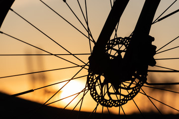 Profile of a bicycle wheel with disc brakes at sunset.