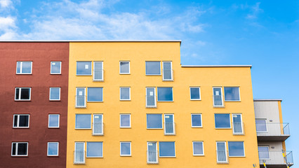 Windows pf red, yellow and white apartment biuldings. Some of the apartments has a french balcony.