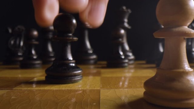 Hand moves pawn on chess board game