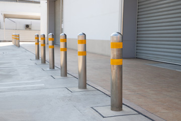 steel bollards with yellow reflec strip near footpath in front of the shutter door. - obrazy, fototapety, plakaty