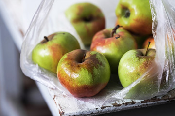 fresh apples in a plastic bag on a white wooden table