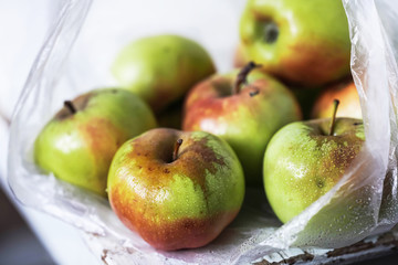 red and yellow apples in a plastic bag close-up on a light background