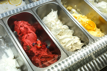 Vaschette nella vetrina di una gelateria con gusti assortiti alla frutta e alla crema
