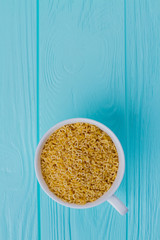 White cup full of letter cereals. Blue wood background and copy space.