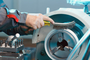 A worker brushes a steel part