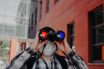 a guy looks through binoculars with different glasses in the center of the city