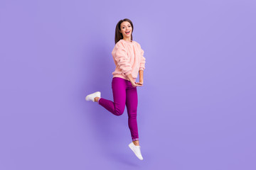 Fototapeta na wymiar Full body profile photo of funny ecstatic lady jumping high up rejoicing spend lovely free time wear casual fur soft sweater pants sneakers isolated purple color background