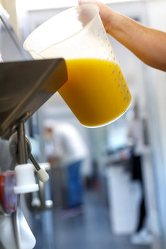 Dettaglio di caraffa con succo darancia che vien versata su un macchinario come ingrediente